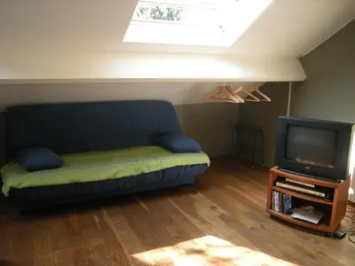a living room with a couch and a tv at Au Bout du Jardin in Waterloo