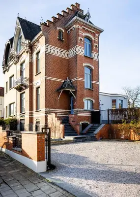 a large brick building with stairs in front of it at Manoir Bel Horizon avec grand jardin et parking privé in Brussels