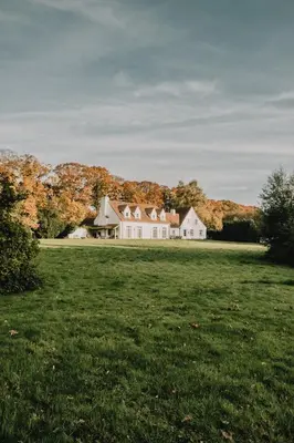 a large white house in a field of grass at Villa Parkbos in De Pinte