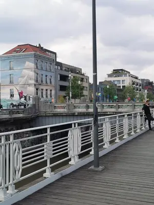 a person walking on a bridge next to a building at Cosy appartement with canal view in Brussels