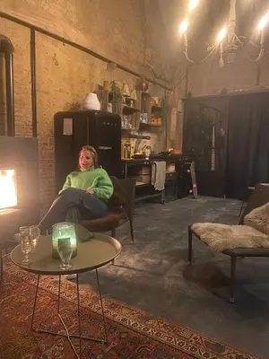a woman sitting in a chair in a living room at B&B Vennehoeve in Vremde