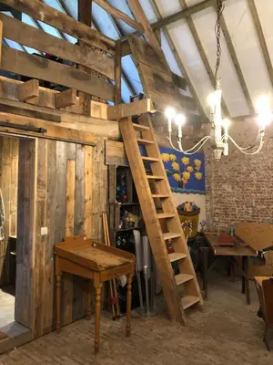 a wooden ladder in a room with tables and tables at B&B Vennehoeve in Vremde