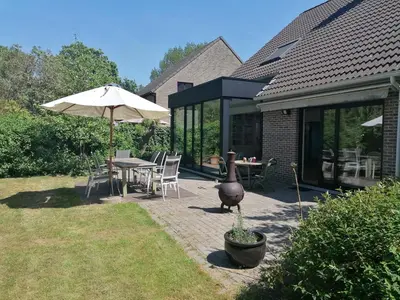 a patio with an umbrella and a table and chairs at villa in Kontich