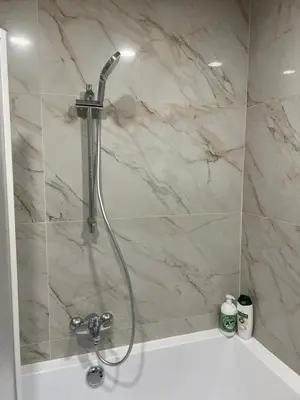a shower in a bathroom with a marble wall at Charming duplex on the canal Brussels in Brussels