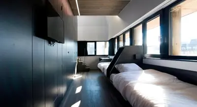 a room with two beds and a tv and windows at Sleep Well Youth Hostel in Brussels