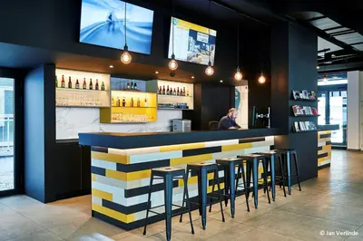 a bar with stools and a man standing behind it at Sleep Well Youth Hostel in Brussels