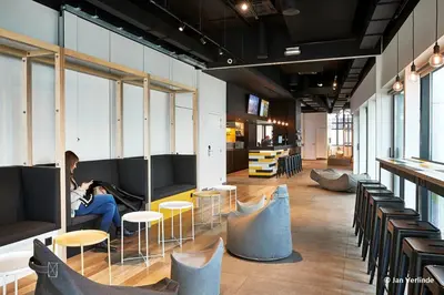 a woman sitting on a couch in a room with chairs at Sleep Well Youth Hostel in Brussels