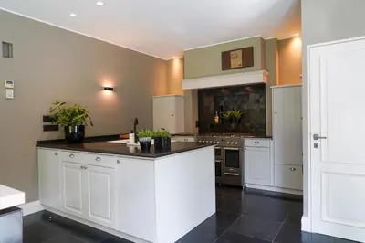 a kitchen with white cabinets and a black counter top at Weynhoven in Brecht