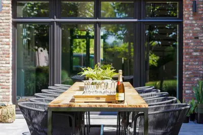 a wooden table with a bottle of wine and chairs at Weynhoven in Brecht