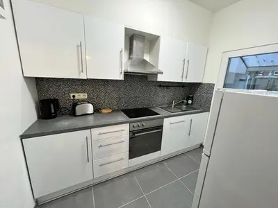 a kitchen with white cabinets and a sink and a refrigerator at Ganha holiday house in Antwerp