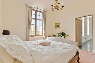 a bedroom with a white bed with a cat laying on it at Huis Potaerde, vakantiewoning op boerderij - luxe landhuis nabij Brussel in Merchtem