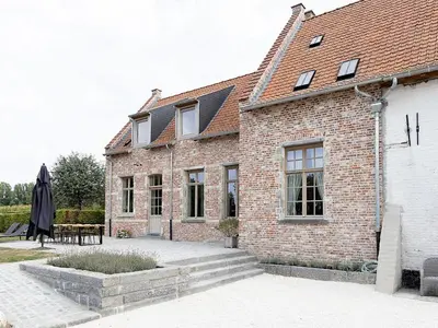 a brick building with a table and an umbrella at Huis Potaerde, vakantiewoning op boerderij - luxe landhuis nabij Brussel in Merchtem