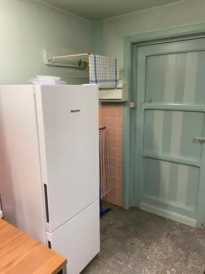 a kitchen with a white refrigerator and a door at Les Barolins in Rotselaar
