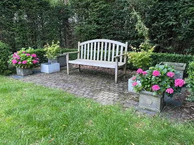 a wooden bench sitting in a yard with flowers at B&B Maison Blanche in Ghent