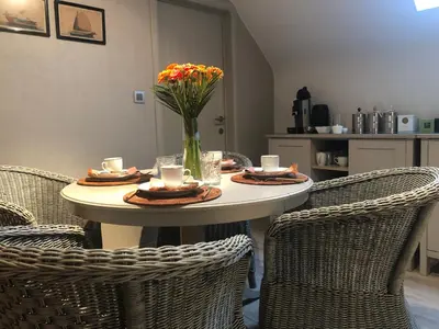 a table with chairs and a vase of flowers on it at B&B Maison Blanche in Ghent