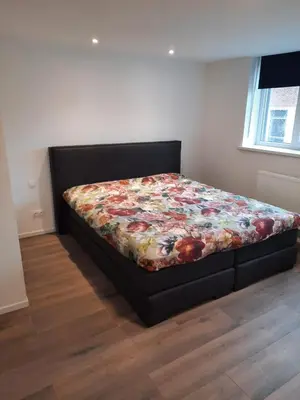 a bed in a bedroom with a flower blanket on it at Sint Andries Duplex in Antwerp