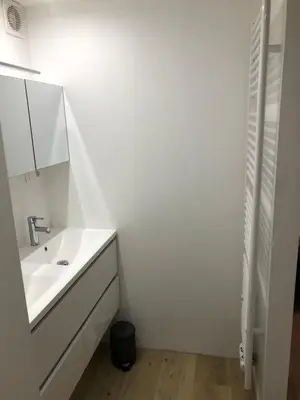 a white bathroom with a sink and a mirror at Sint Andries Duplex in Antwerp