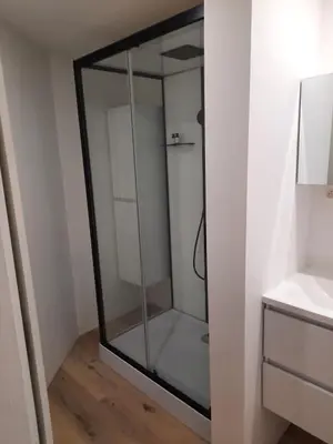 a glass shower in a room with a wooden floor at Sint Andries Duplex in Antwerp