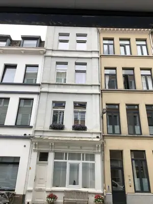 a white building with windows and flowers in front of it at Sint Andries Duplex in Antwerp