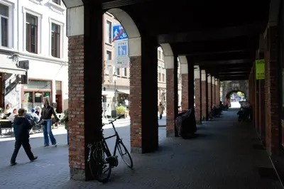 a person walking down a street with a bike in an arcade at Historical center Antwerp, all on foot in Antwerp