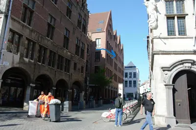 a group of people walking down a city street at Historical center Antwerp, all on foot in Antwerp