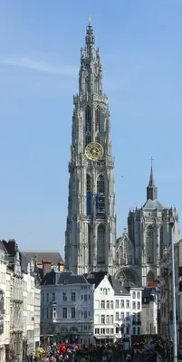 a large cathedral with a clock tower in a city at On our way to Antwerp, first stop in Mortsel