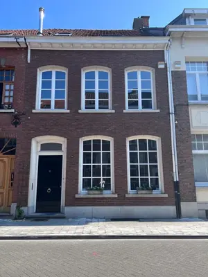 a brick building with a black door and windows at Maison Georges in Turnhout