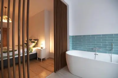 a bathroom with a bath tub and a bedroom at Vakantiehuis huYze-K in Zottegem