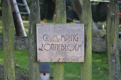 a sign on a wooden fence with the words swingingnotation at Glamping Zonnebloem - Back-to-Nature in Herzele
