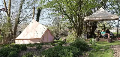 a woman sitting in a garden with a tent at Glamping Zonnebloem - Back-to-Nature in Herzele