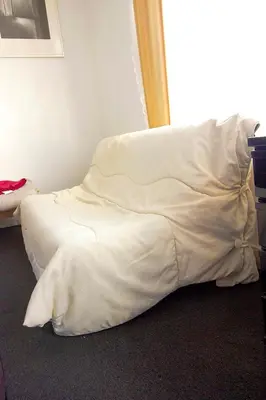 a bed with white sheets sitting in a room at Handy Studio close to Zaventem airport in Brussels