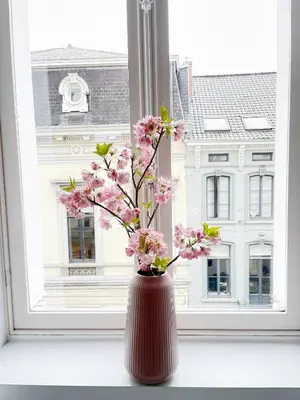 a brown vase with pink flowers in a window at Jacob’s Getaway in Ghent