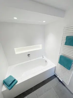 a white bathroom with a bath tub with blue towels at Jacob’s Getaway in Ghent