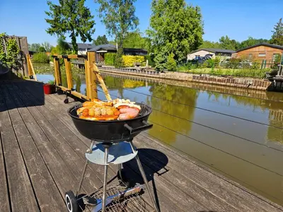 a wheelbarrow of food sitting on a dock next to a river at Le Canard - Rust aan het water in Geel