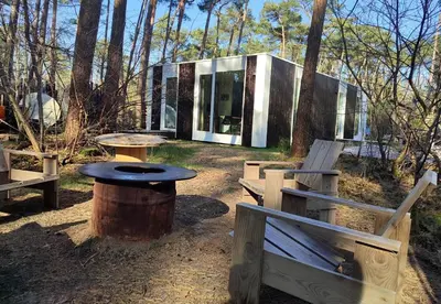 a house in the woods with a table and benches at White Box in Gierle