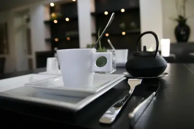 a table with a white coffee cup and a saucer at Hotel Domus in Boom