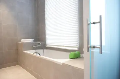 a bathroom with a tub and a window with a green bowl at Hotel Domus in Boom