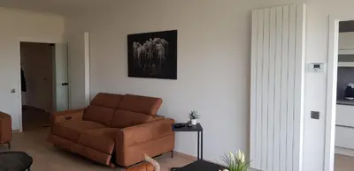 a living room with a brown couch and a table at Gezellig appartement Beveren Kruibeke Zwijndrecht Donkvijver in Beveren