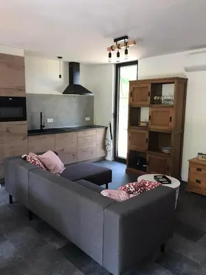 a living room with a gray couch and a kitchen at Vakantiewoning De Kleine Duinberg - Chalet Nr 9 in Retie