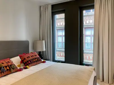 a bedroom with a bed with two pillows and two windows at Apartment in the Heart of Ghent in Ghent