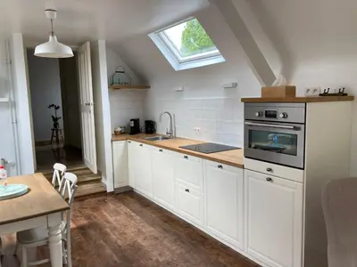 a kitchen with white cabinets and a sink and a window at Rustig appartement in het groen met terras in Kontich