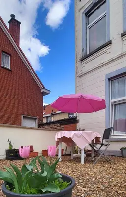a patio with a pink umbrella and a table and chairs at Bright studio close to Zaventem airport in Brussels