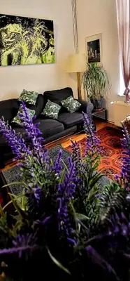 a living room with purple flowers and a couch at Bright studio close to Zaventem airport in Brussels
