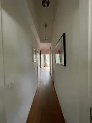 a hallway with white walls and wooden floors and paintings at Great house 5' from Tomorrowland in Rumst