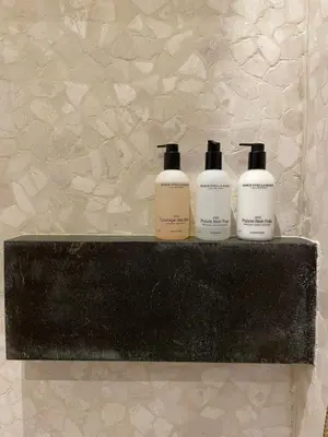 a shelf with three shampoo bottles on it at B&b kleinen bosch in Beveren