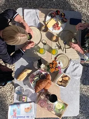 a table with plates of food and people drinking wine at B&b kleinen bosch in Beveren