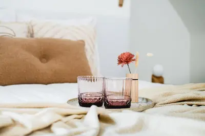 a table with two glasses and a vase on a bed at B&b kleinen bosch in Beveren