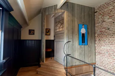 a hallway with a wooden door and a brick wall at B&b kleinen bosch in Beveren