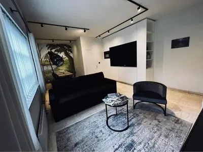 a living room with a black couch and a chair at Guesthouse Ter Linden in Bazel