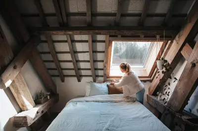a woman sitting on a bed in a room with a window at Pañ boetiek BnB in Zele